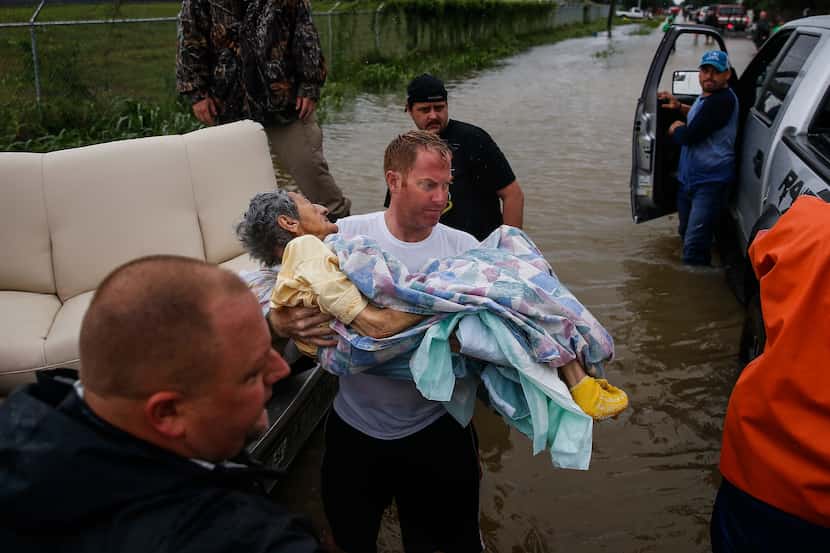 A rescuer moves Paulina Tamirano, 92, from a boat to a truck bed as people evacuate from the...