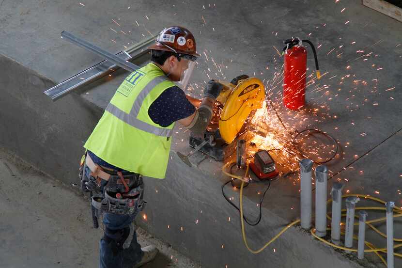 Sparks fly as a worker cuts a metal pipe in the arena area of Texas Live! in Arlington. The...