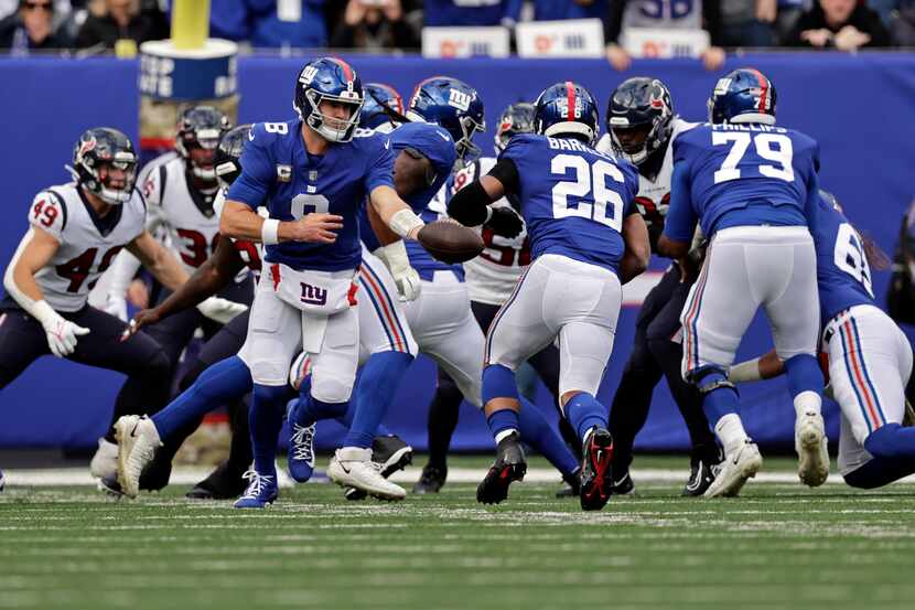 New York Giants quarterback Daniel Jones (8) hands off to Saquon Barkley (26) against the...