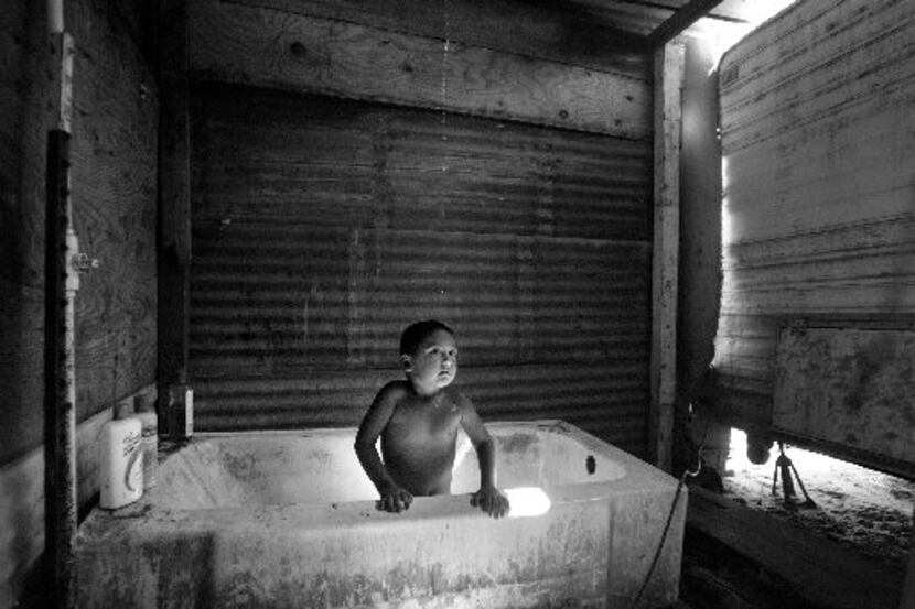 A 3-year-old patiently waits for the dribble of water to reach him in the family's shower,...