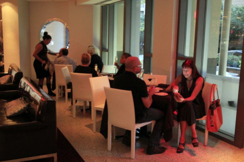 A patron reads her phone, as she and a other customers enjoy their meals and wine inside Dee...