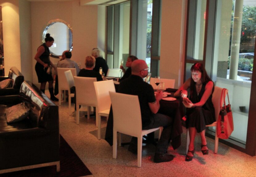 A patron reads her phone, as she and a other customers enjoy their meals and wine inside Dee...