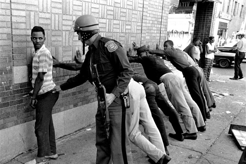  A Michigan State police officer searches a youth on Detroit's 12th Street where looting was...