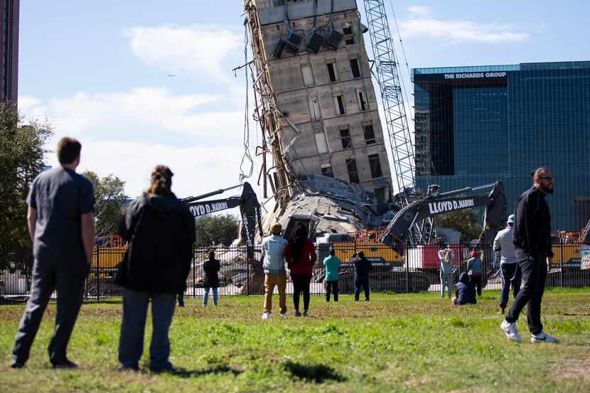 A crowd watches as a wrecking ball chips away at the top levels of the former Affiliated...