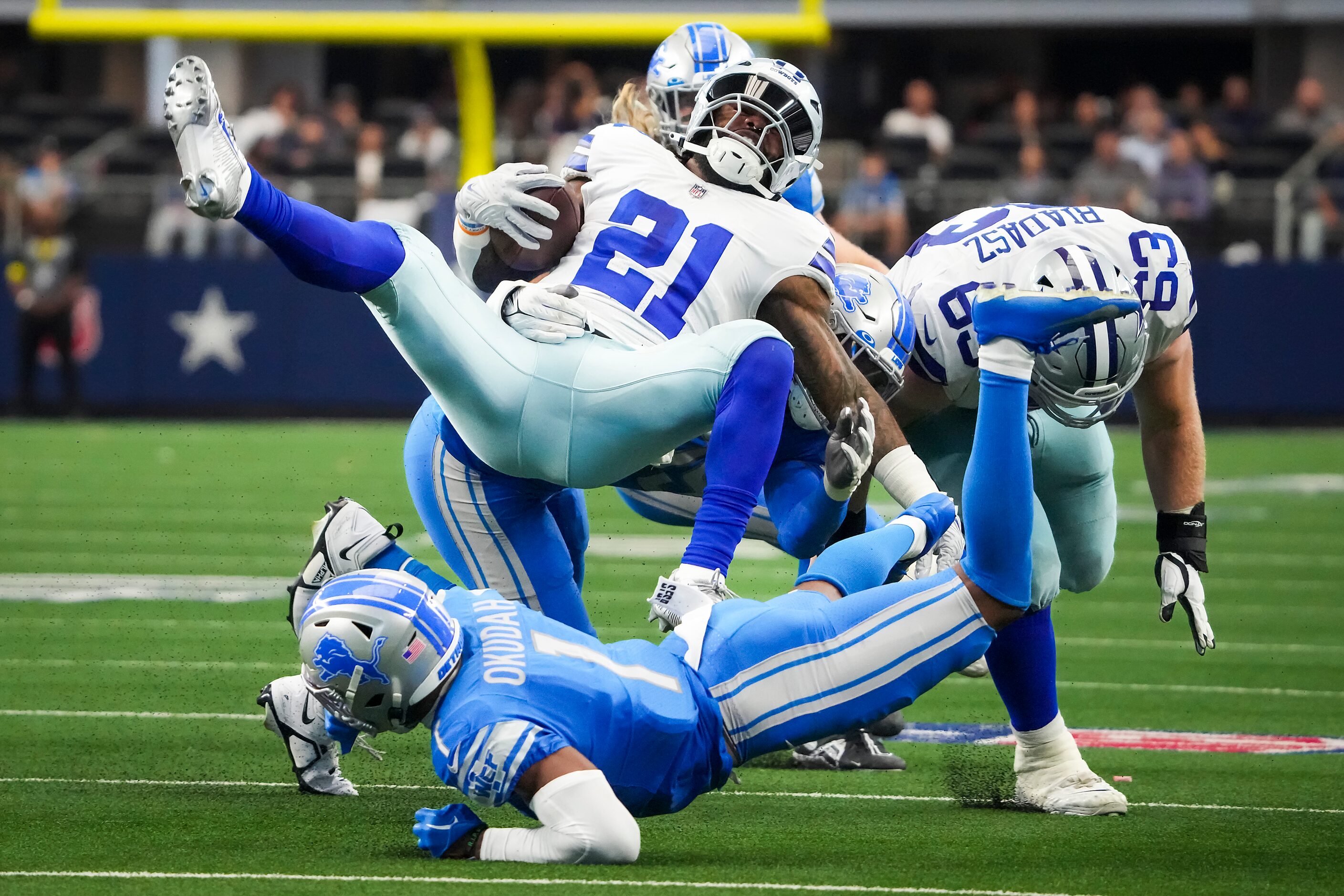 Dallas Cowboys running back Ezekiel Elliott (21) is knocked off his feet by Detroit Lions...