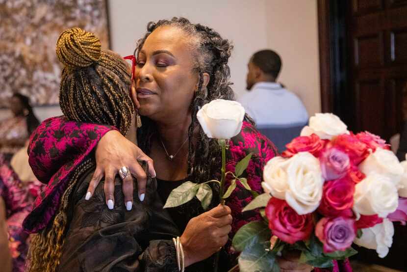 Cheryl Polote Williamson (right) receives a hug and flowers at the Women of Influence luncheon.