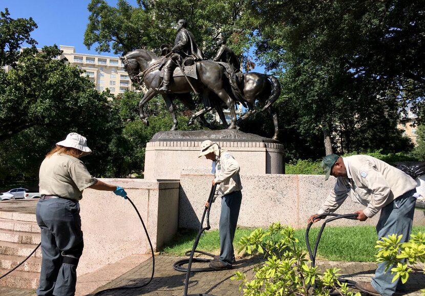 Dallas Parks department workers pack up after removing graffiti from the Robert E. Lee...