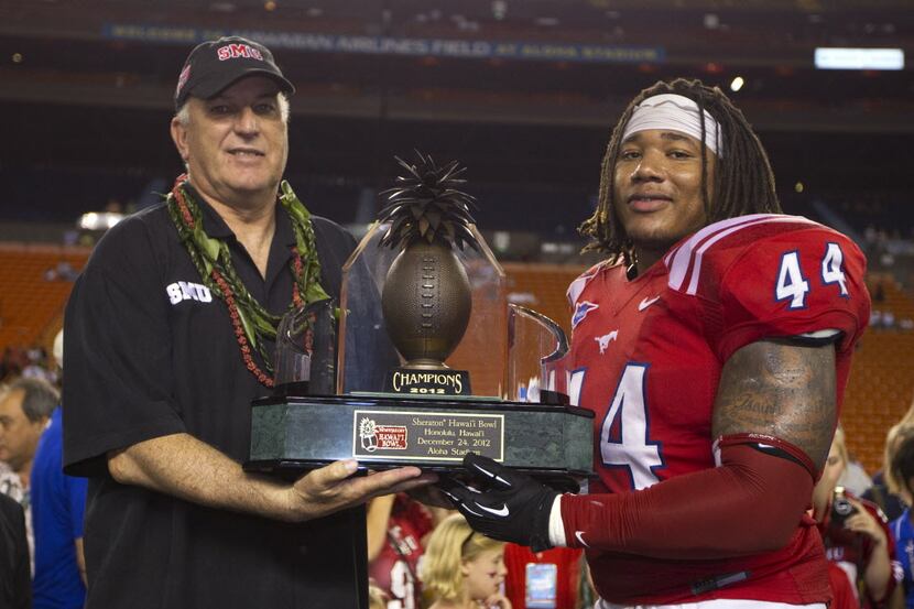 SMU coach June Jones and linebacker Taylor Reed (44) hold the Hawaii Bowl trophy after SMU...