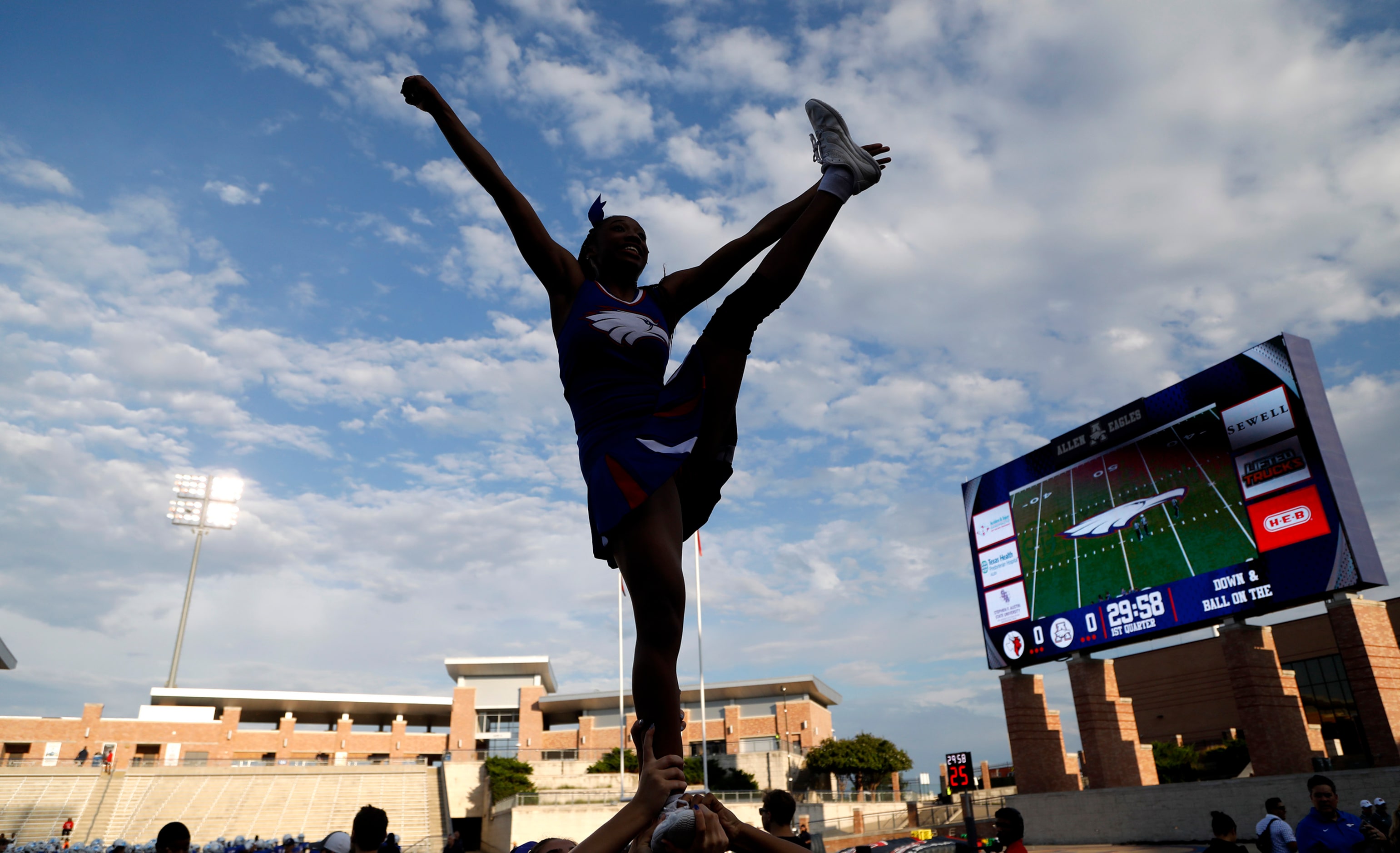 Allen High School varsity cheeleader Aaliyah Smith, 15, cheers against a clear sky before...