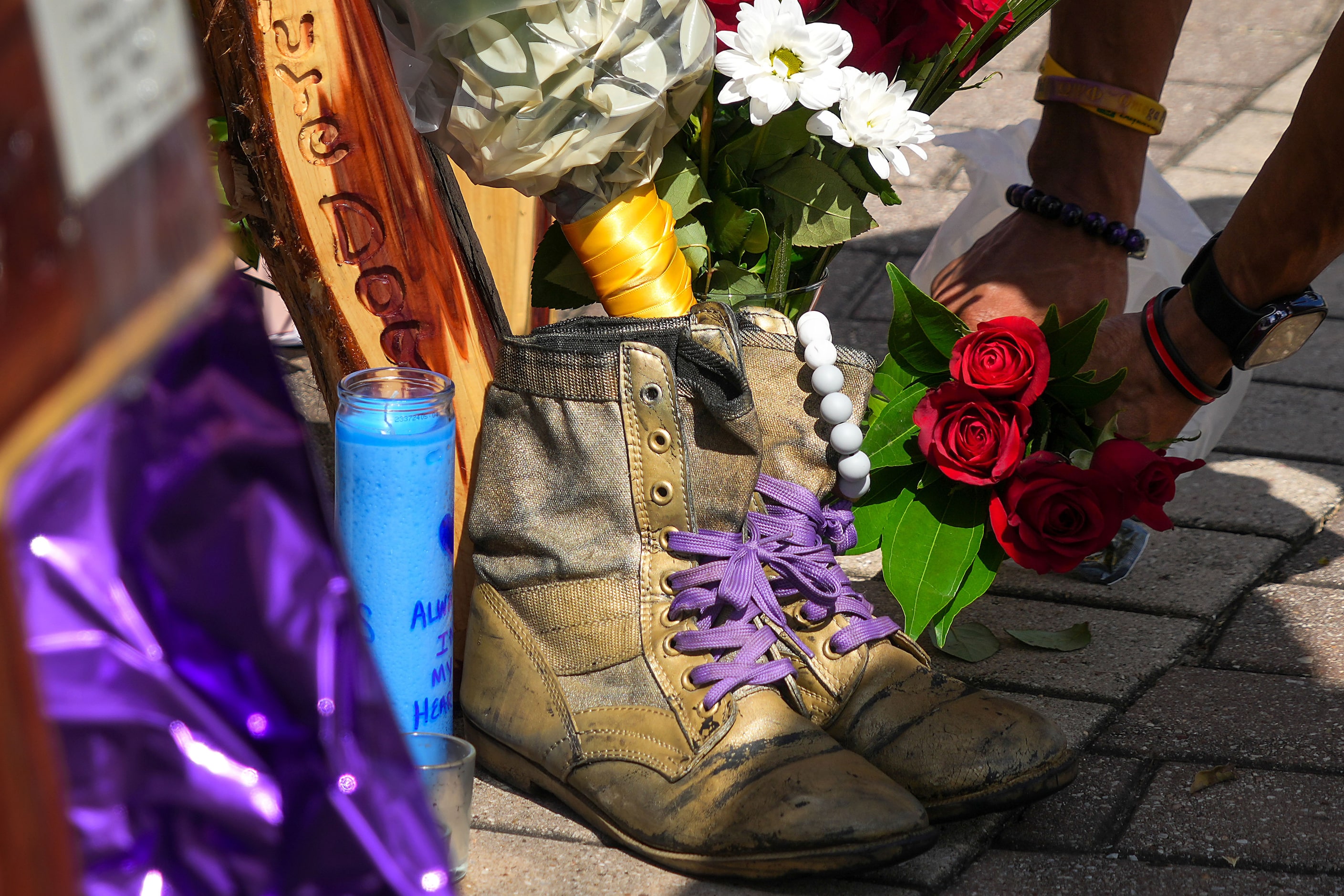 A mourner places roses next to the fraternity boots of slain Dallas police officer Darron...