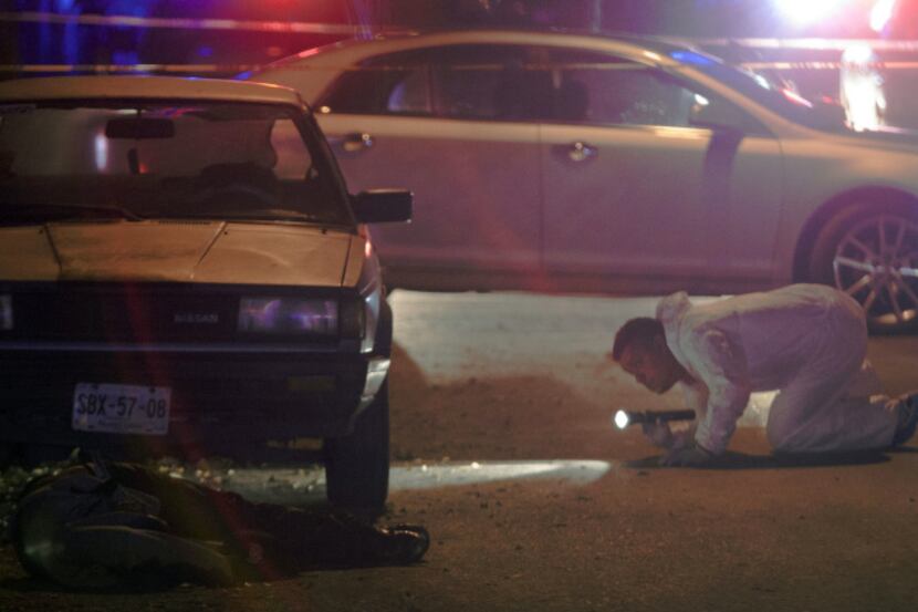 A forensic service officer examined one of four corpses at a crime scene in Monterrey last...