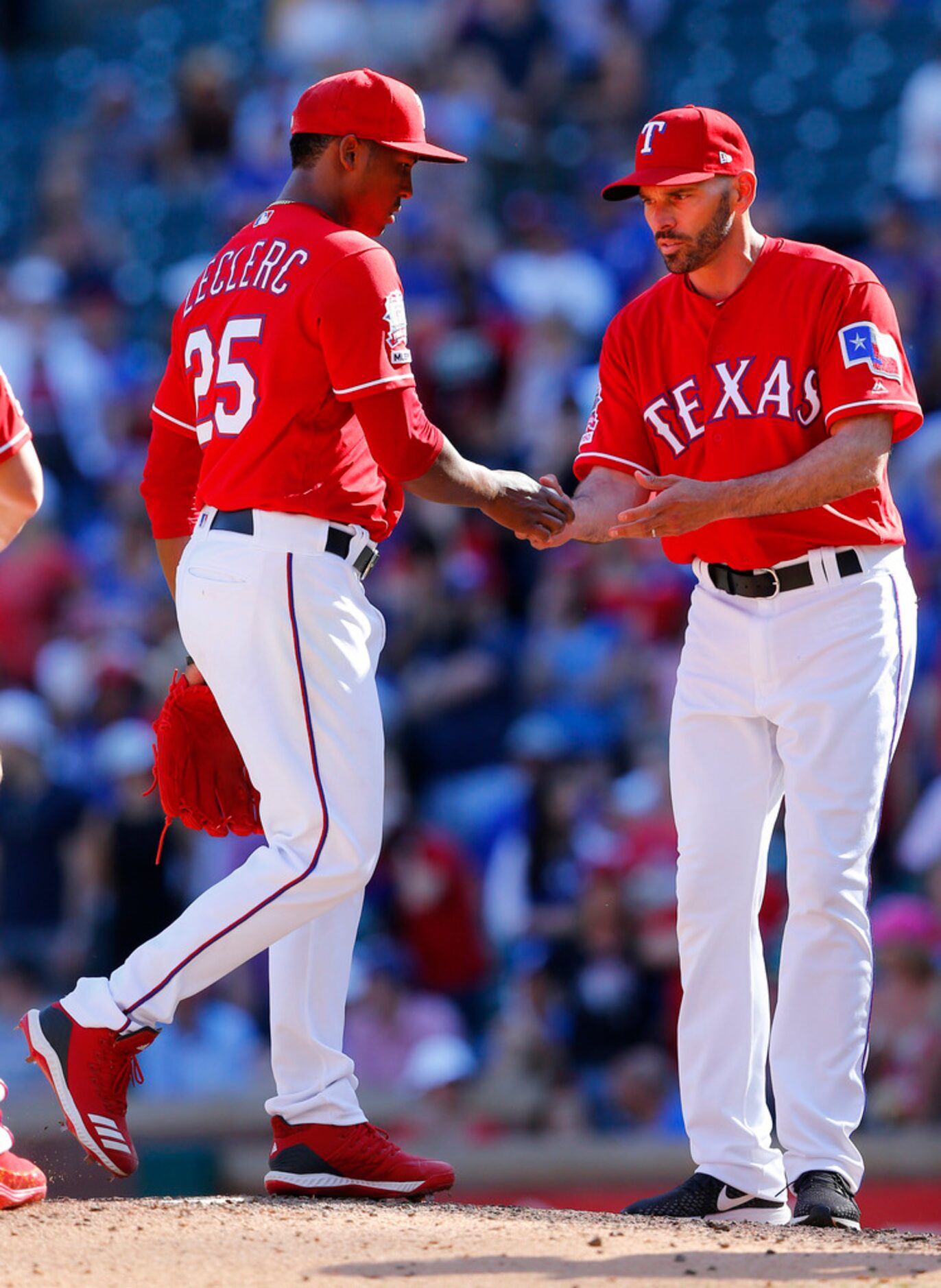 Texas Rangers relief pitcher Jose Leclerc (25) hands the ball to manager Chris Woodward as...