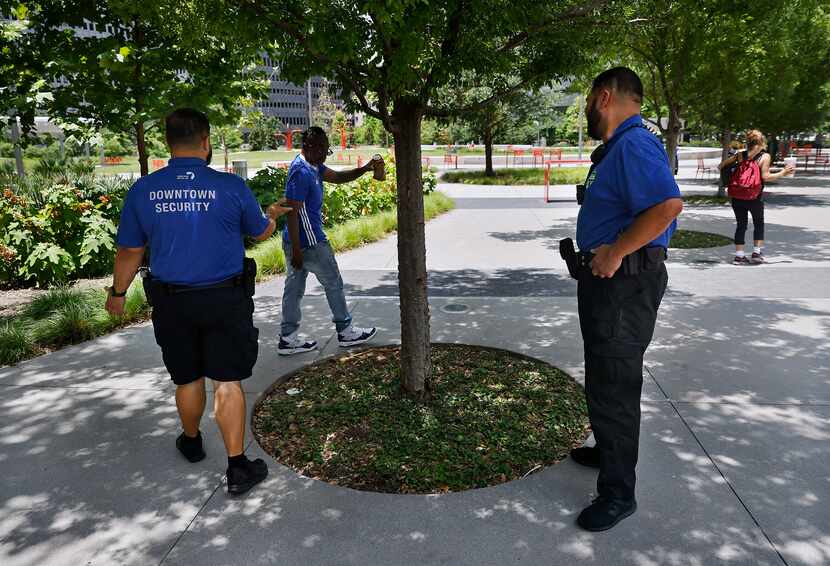 Downtown Dallas Inc. public safety officers instruct a man to pour out his beer as they...