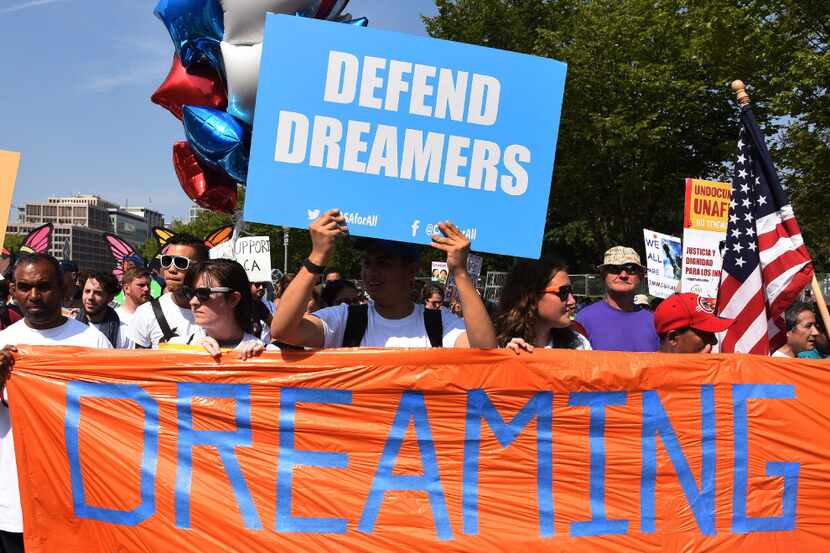 Protesters hold up  signs during a rally supporting Deferred Action for Childhood Arrivals,...