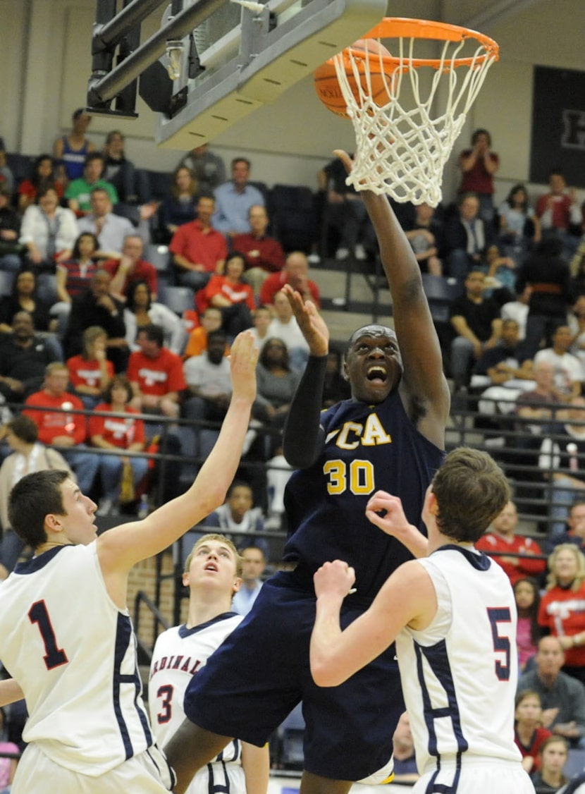 Prestonwood's Julius Randle (30) drives to the basket between John Paul II's Matt Thompson...