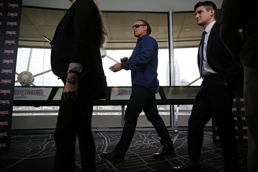 WWE Superstar Sting (center) walks between media interview stations during a press event...