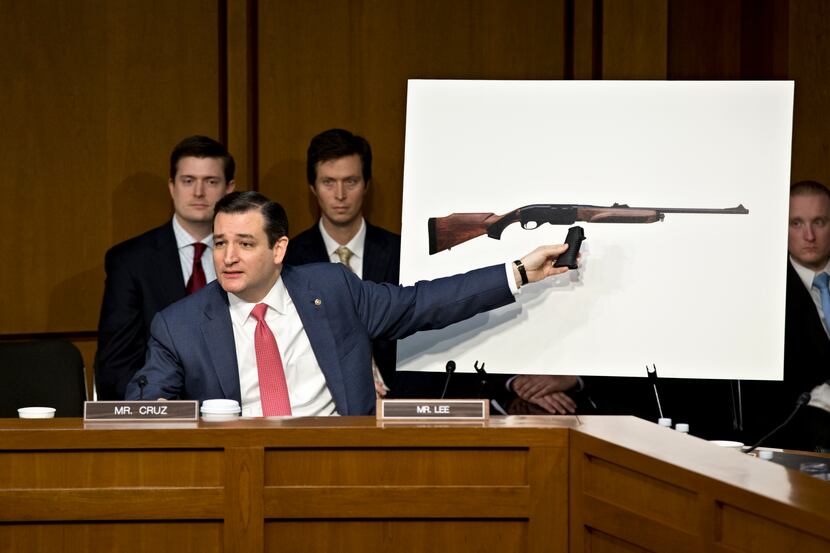 Texas Sen. Ted Cruz holds a pistol grip up to a life-size photo of a Remington 750, a...