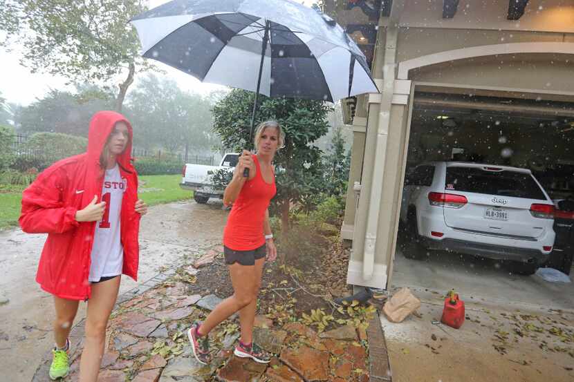 Abby Odneal, left, and her mother Ashley dodge raindrops to view the damage on the family...