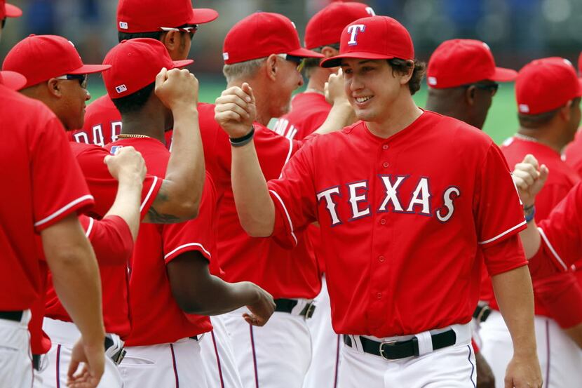 Texas Rangers starting pitcher Derek Holland (45) slaps hands with teammates during team...