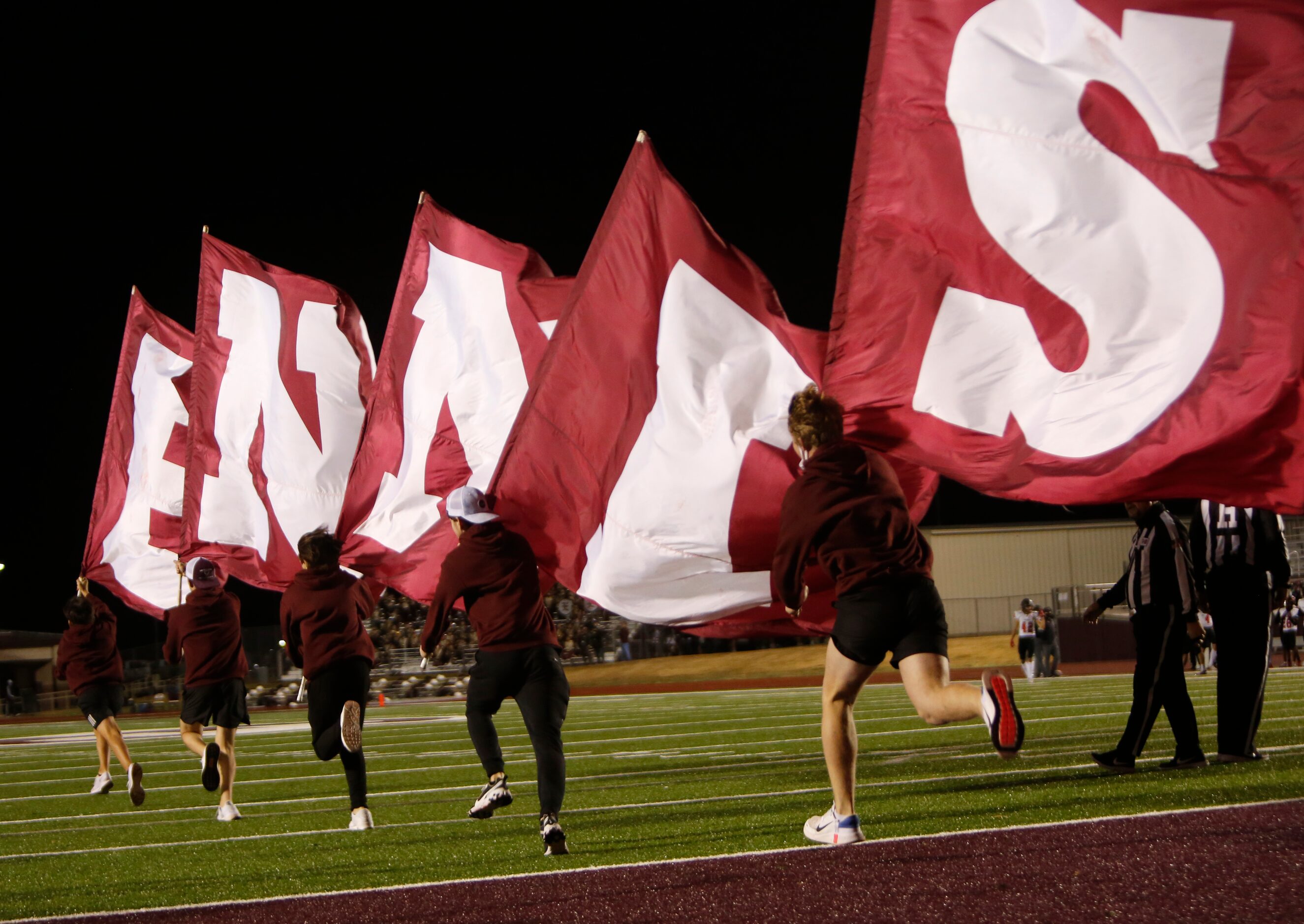 Ennis Lions supporters race onto the field with flags following one of the team's first half...