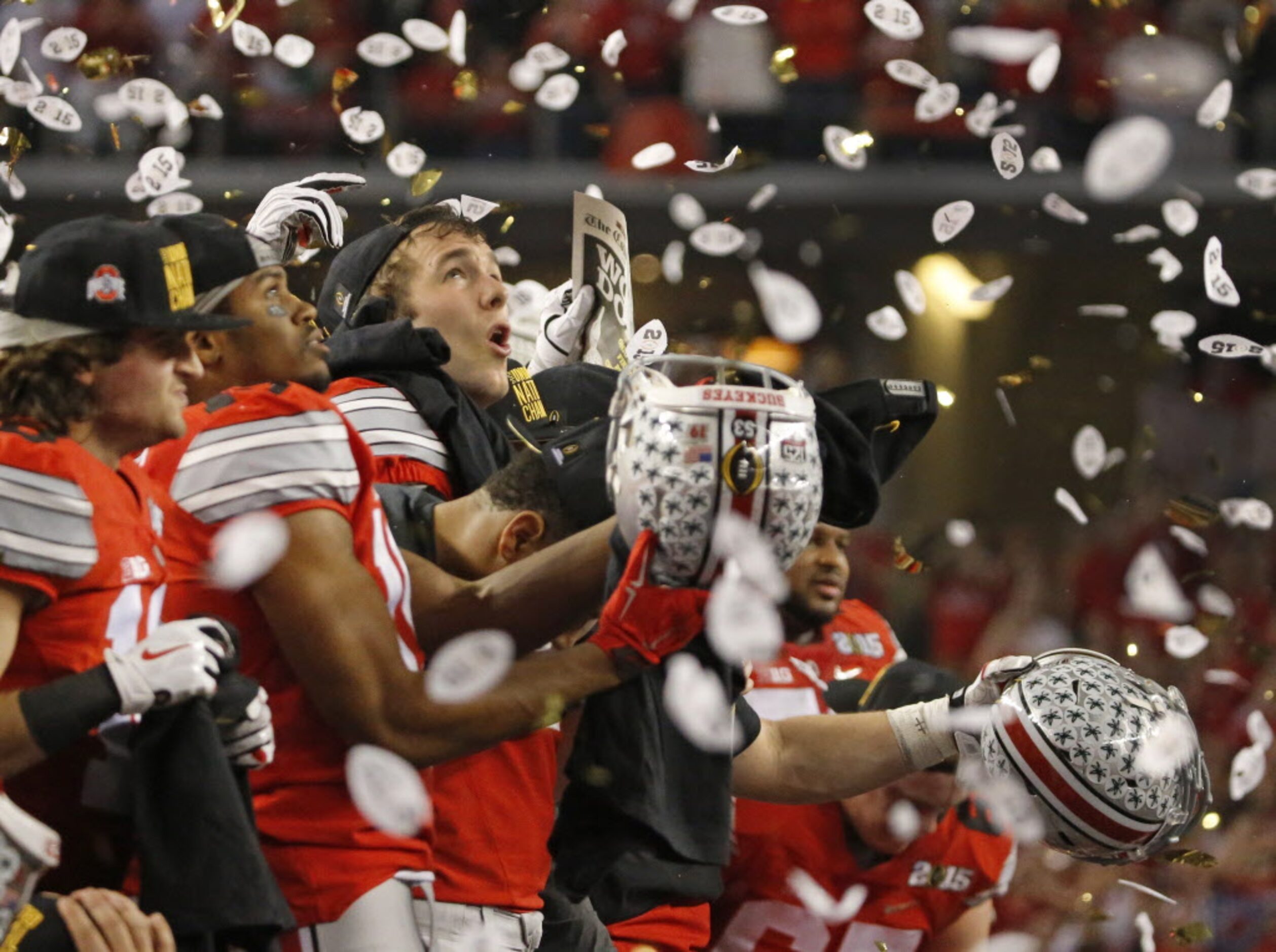 Ohio State Buckeyes players tryto collect confetti in their helmets after the Buckeyes'...