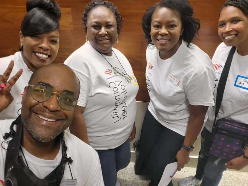 Five Bank of America volunteers, on of whom is making a peace sign, pose wearing white...