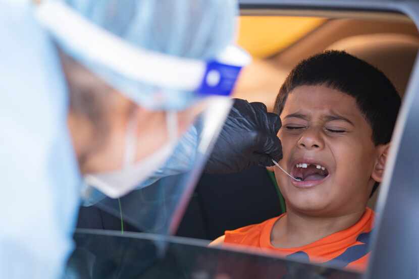 Elizabeth Osborn, medical assistant at WellHealth, swabs Josiah Soto's mouth for COVID-19 at...