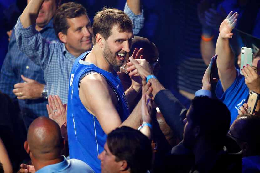 Dallas Mavericks forward Dirk Nowitzki slaps hands with fans following a postgame ceremony...