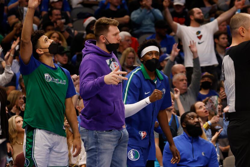 Dallas Mavericks guard Luka Doncic (77) cheers on from the bench as the team plays against...