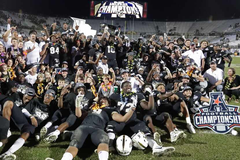 Central Florida players, coaches and family members celebrate after defeating Memphis in the...