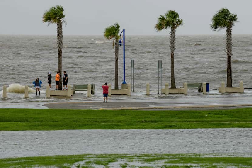 People check out the waves on Lakeshore Drive in New Orleans on Friday as water moves in...