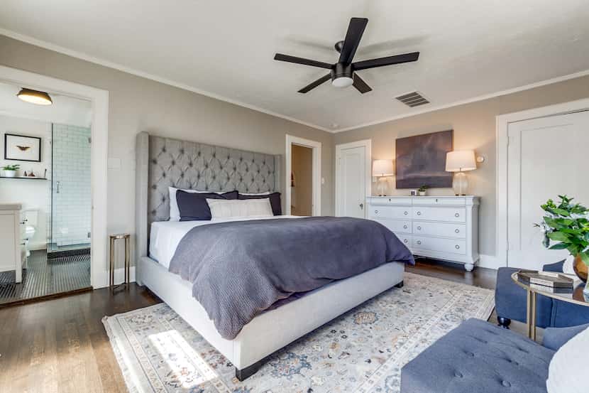 A large bed is centered in a bedroom in this 1928 home. To the left of the bed, there's a...