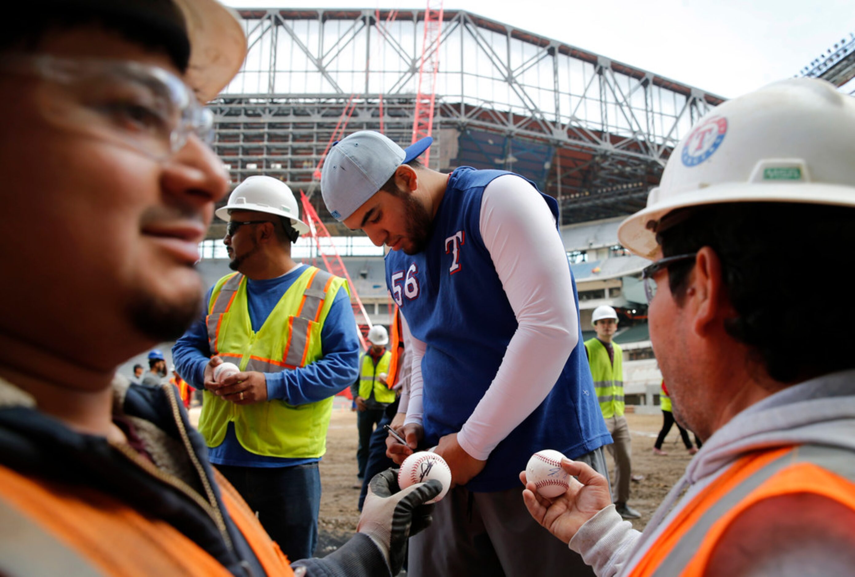 Texas Rangers Jose Trevino signs baseballs for members of the construction crew at Globe...