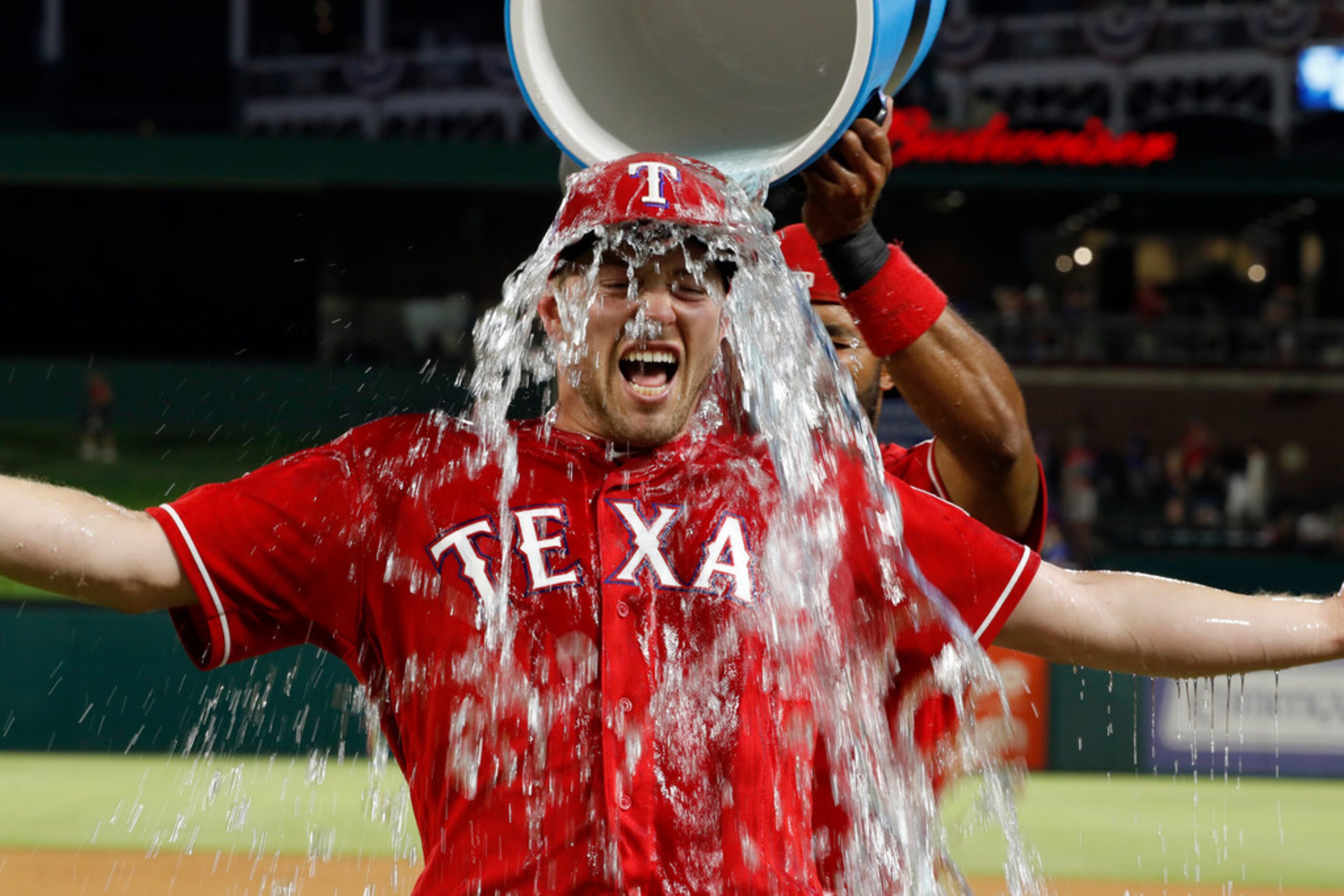 Texas Rangers' Adrian Sampson is doused by Elvis Andrus, rear, after the second baseball...