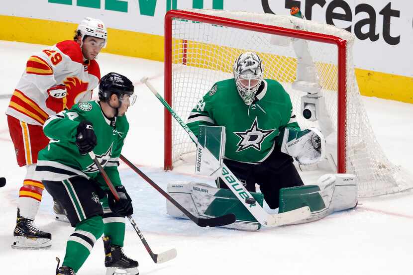 Dallas Stars goaltender Jake Oettinger (29) deflects a shot by Calgary Flames center Mikael...
