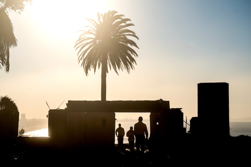 Firefighters from an Oregon strike team survey damage at a Sunset Blvd. home leveled by the...