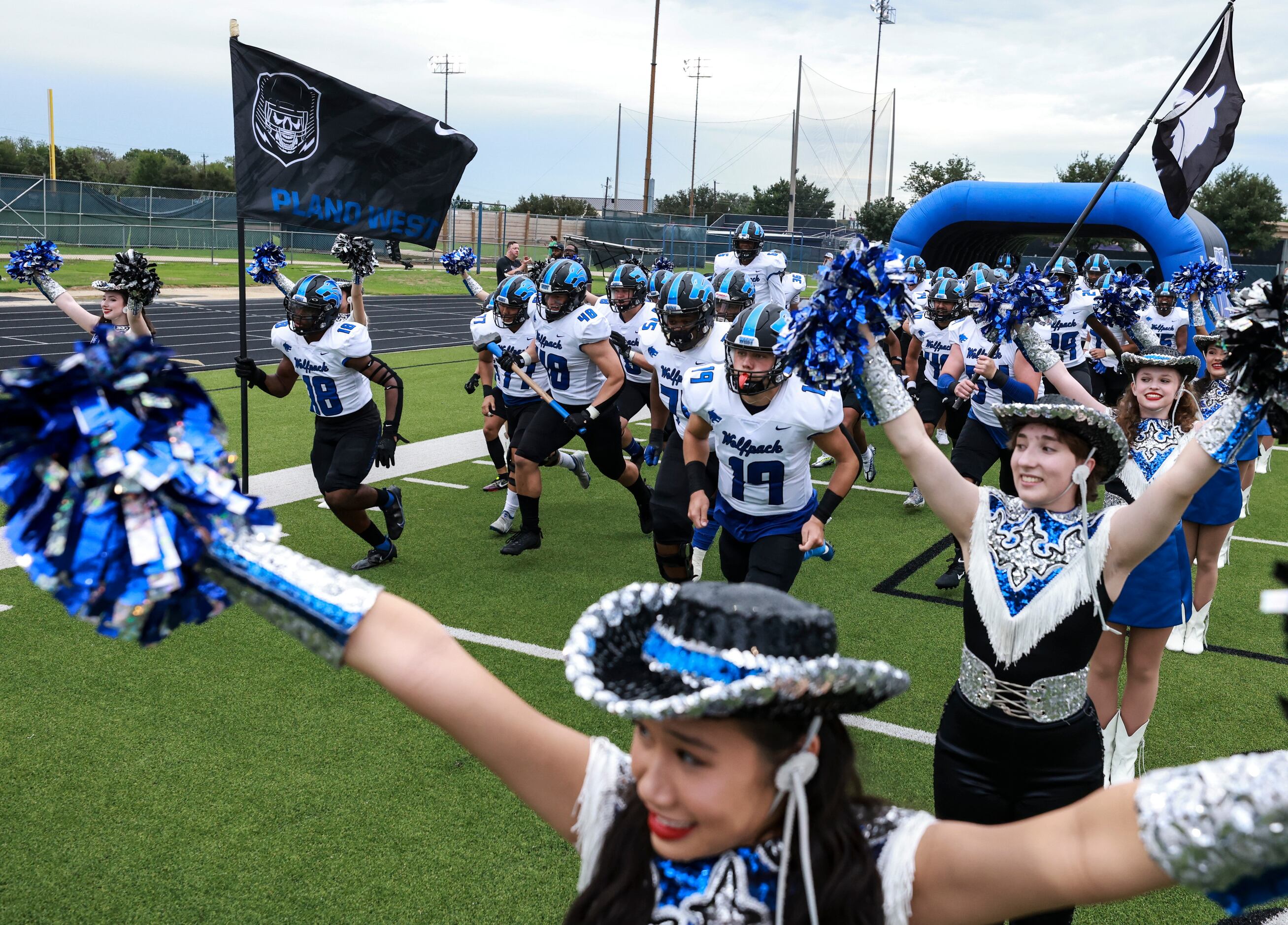 Plano West Senior High players run on the field before the football game between Keller High...