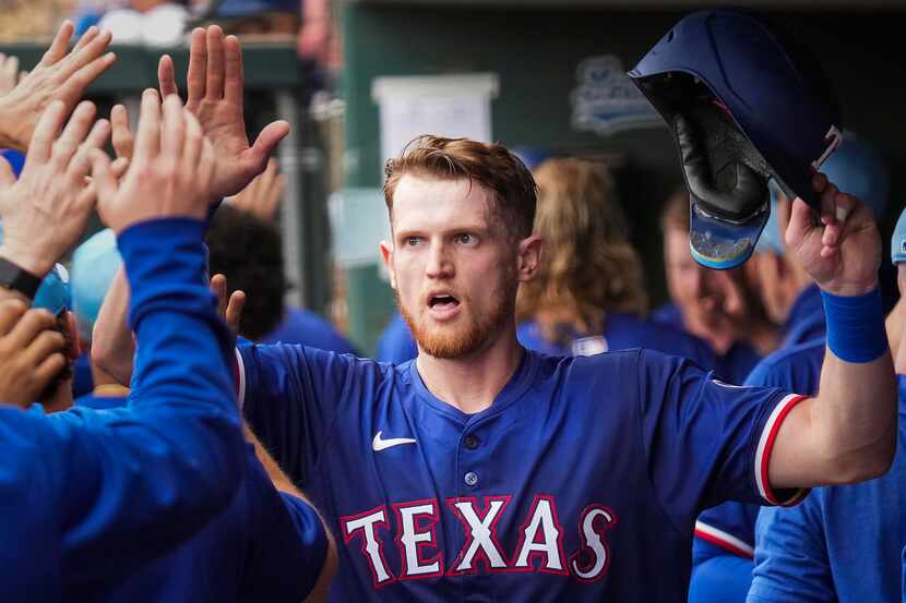 Texas Rangers catcher Sam Huff celebrates with teammates as he returns to the dugout after...