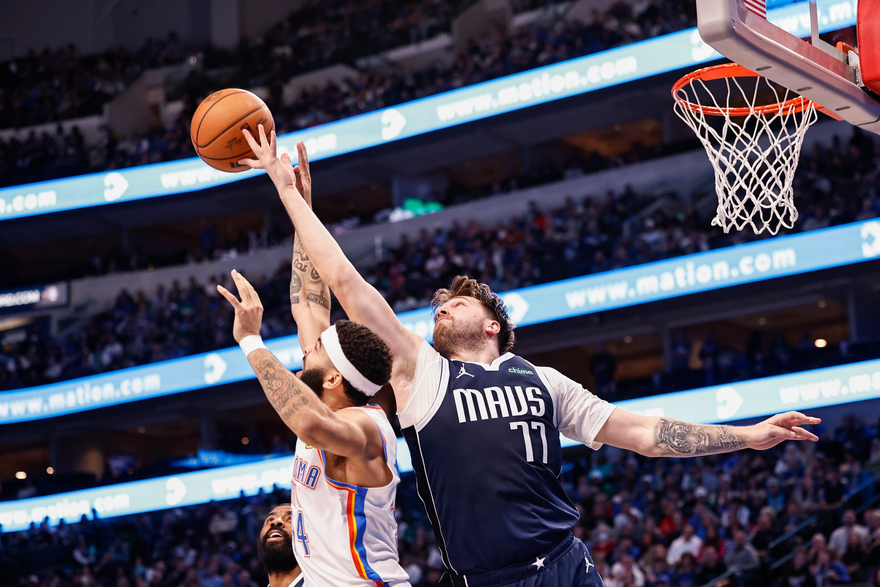 Dallas Mavericks guard Luka Dončić (77) reaches for the rebound over Oklahoma City Thunder...