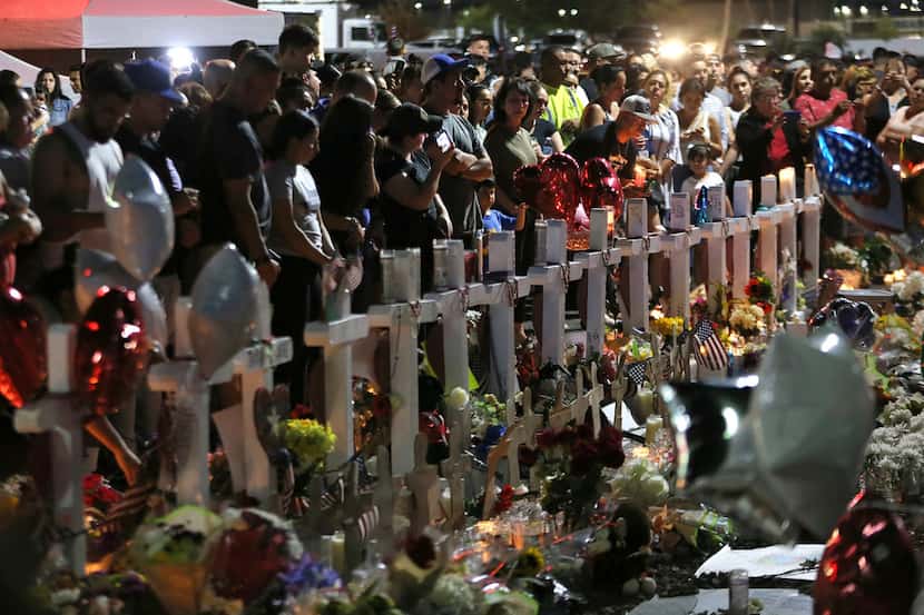 Hundreds of people hold vigil Aug. 5, 2019, outside the Walmart in El Paso, where a mass...