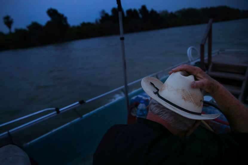 Father Roy Snipes holds down his cowboy hat as the wind gusts while he motors down the Rio...