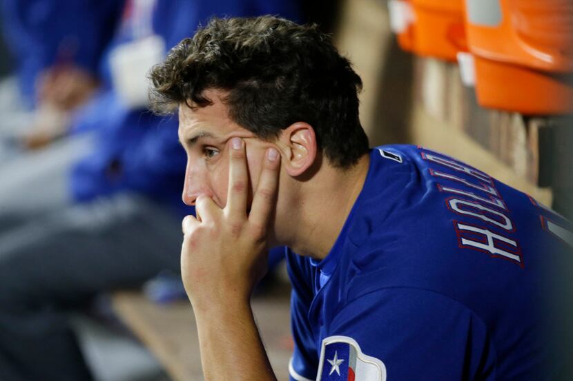 Texas Rangers starting pitcher Derek Holland sits in the dugout after being pulled from a...