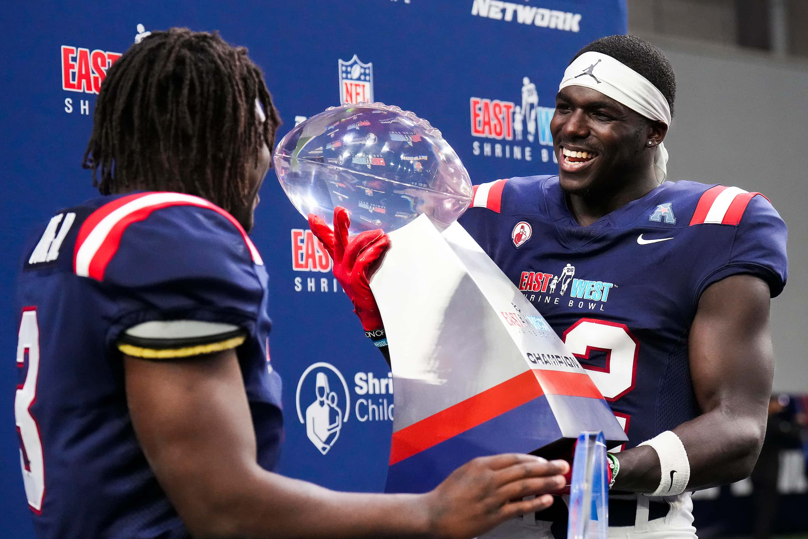 West defensive back Jarius Monroe of Tulane  (32) lifts the game trophy with West running...