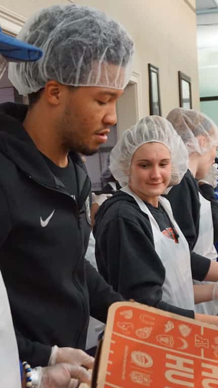 Mavericks' rookie guard Jalen Brunson helps workers distribute 2,000 pizzas to first...