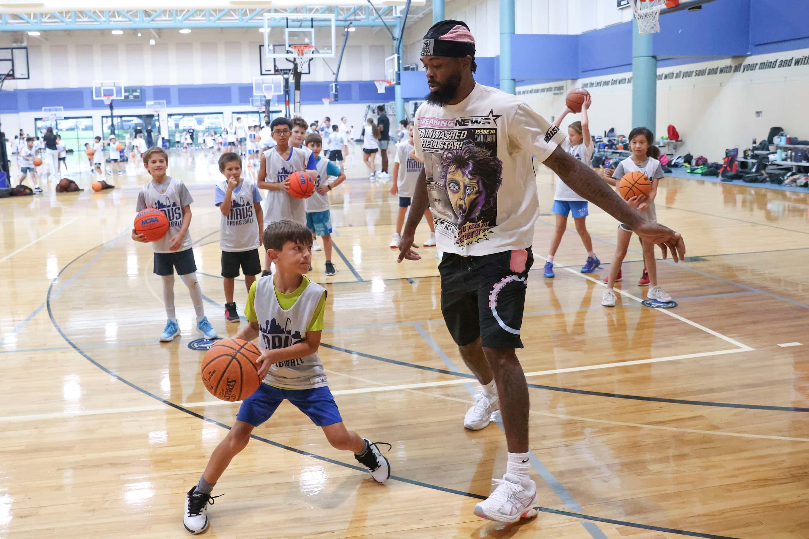 Dallas Mavericks’ Naji Marshall, defends white playing ball with young basketball campers...