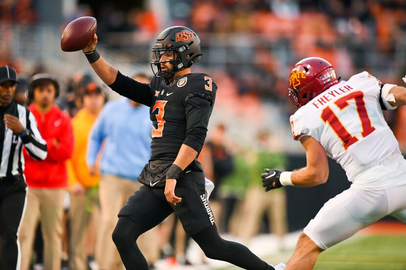 Oklahoma State quarterback Spencer Sanders (3) holds up the ball while running out of bounds...