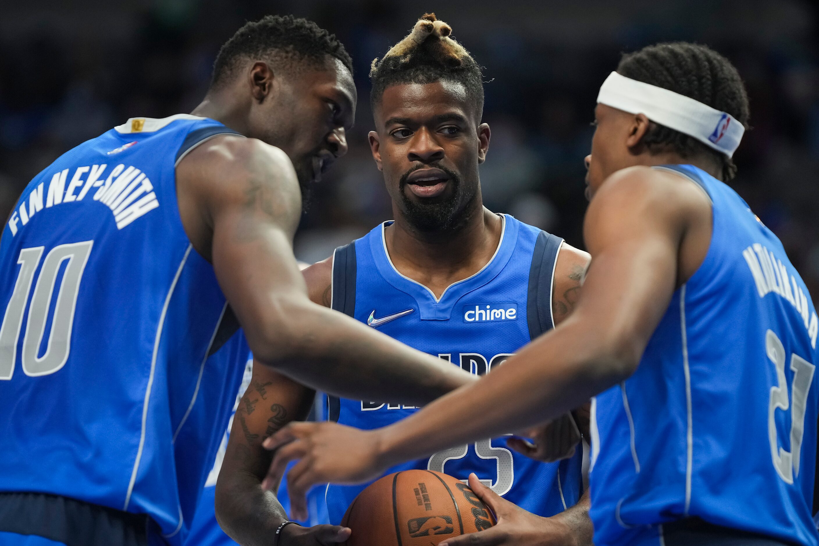 Dallas Mavericks forward Reggie Bullock (25) huddles with forward Dorian Finney-Smith (10)...