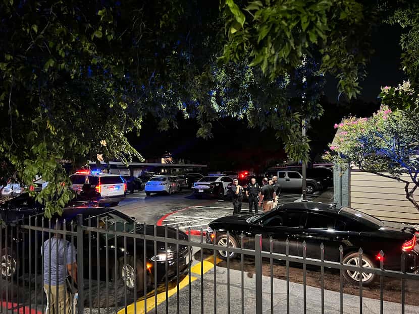 Dallas police officers gathered in a parking lot between apartment buildings after officers...