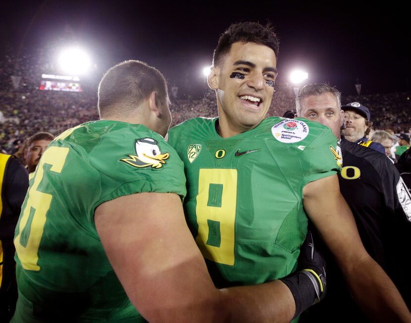 Oregon quarterback Marcus Mariota, right, celebrates with offensive lineman Jake Pisarcik...