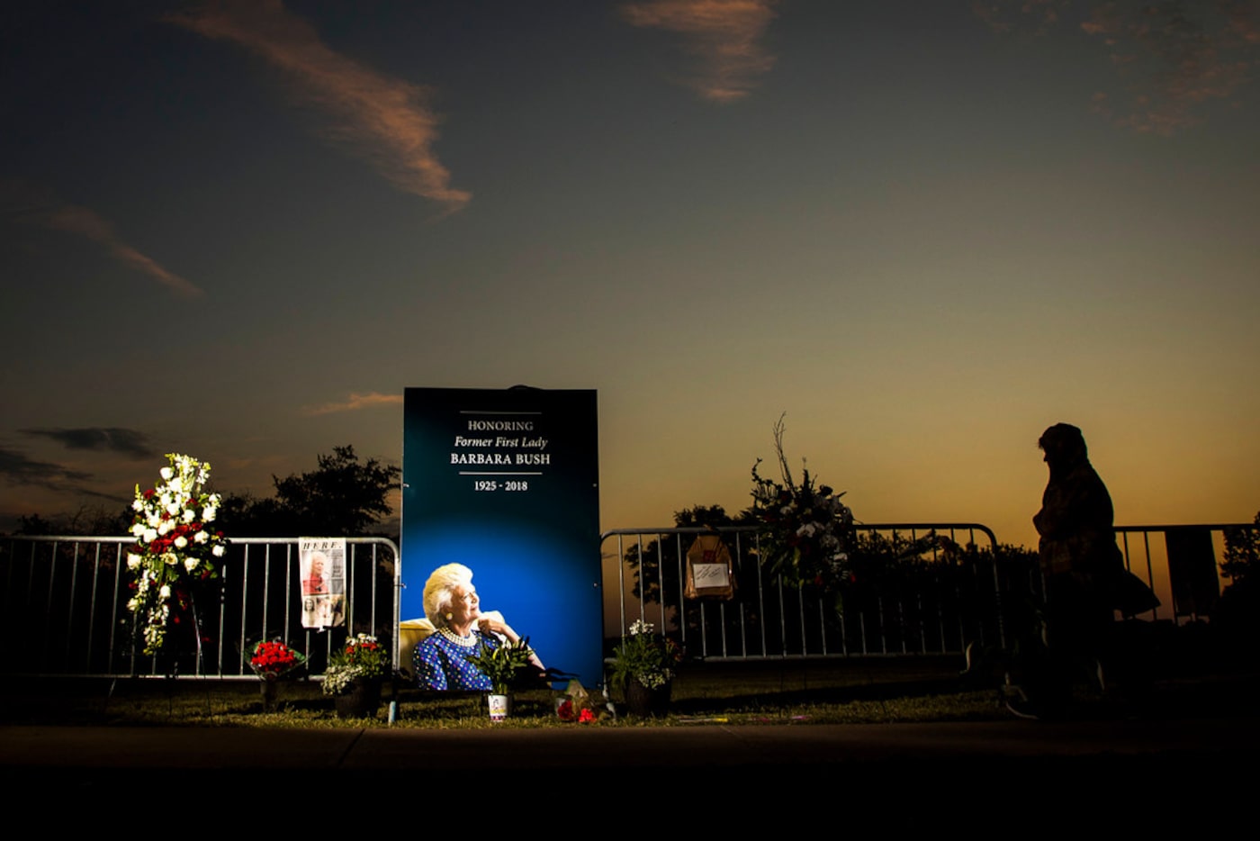 People visit a memorial to former first lady Barbara Bush as the sun sets near her husband's...